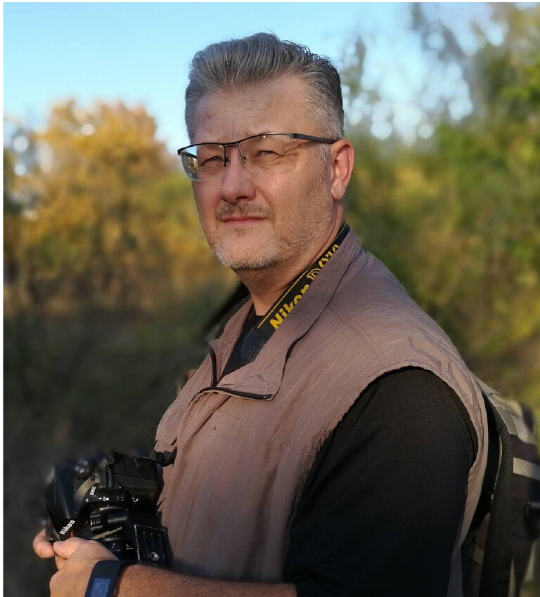 Wildlife photographer Dennis Stewart holding his camera in the field