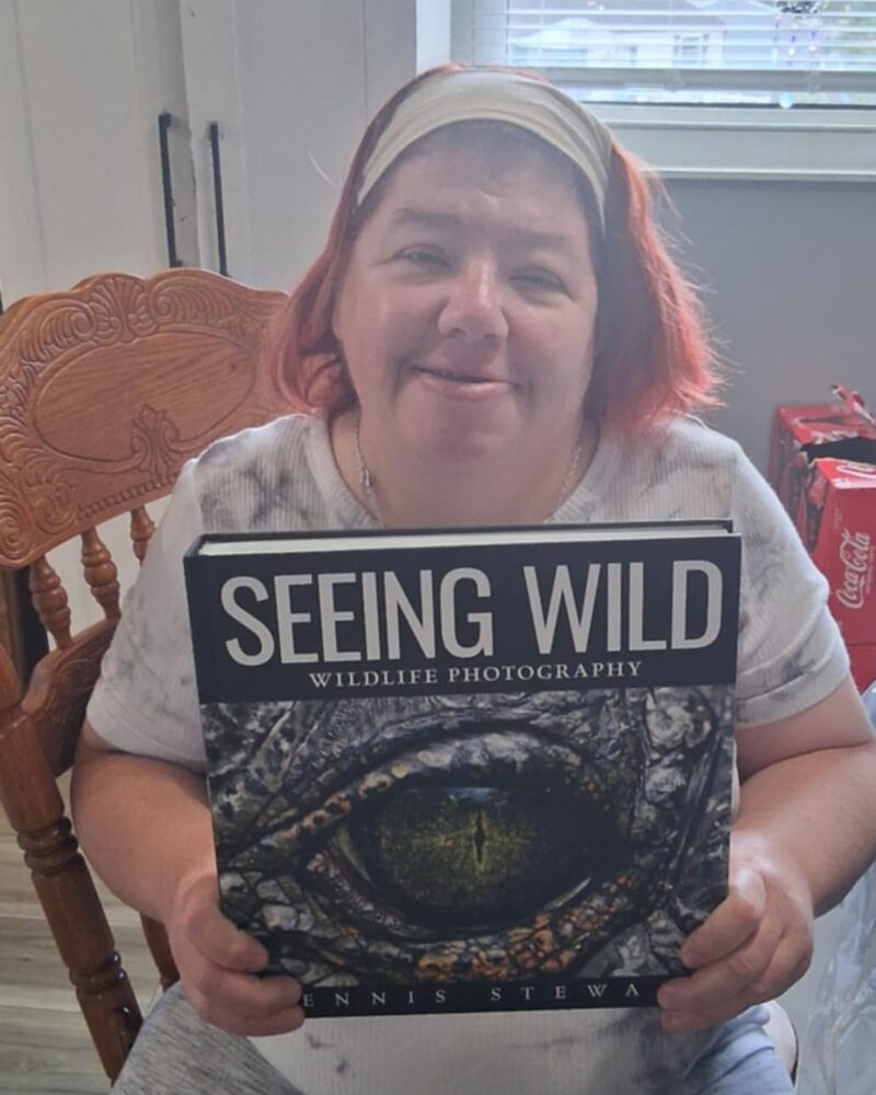 Reader seated at home holding Seeing Wild