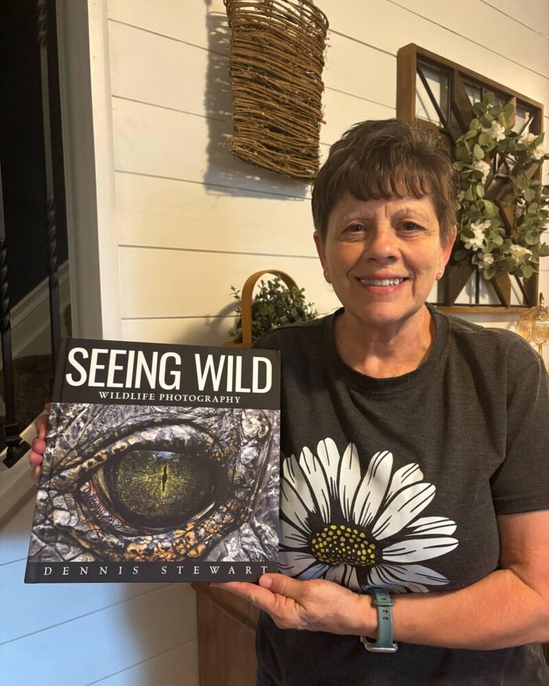 Reader in a floral shirt holding Seeing Wild