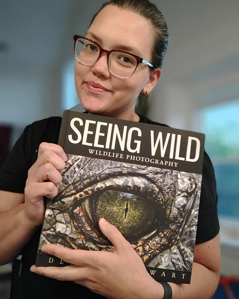 Reader wearing glasses holding Seeing Wild