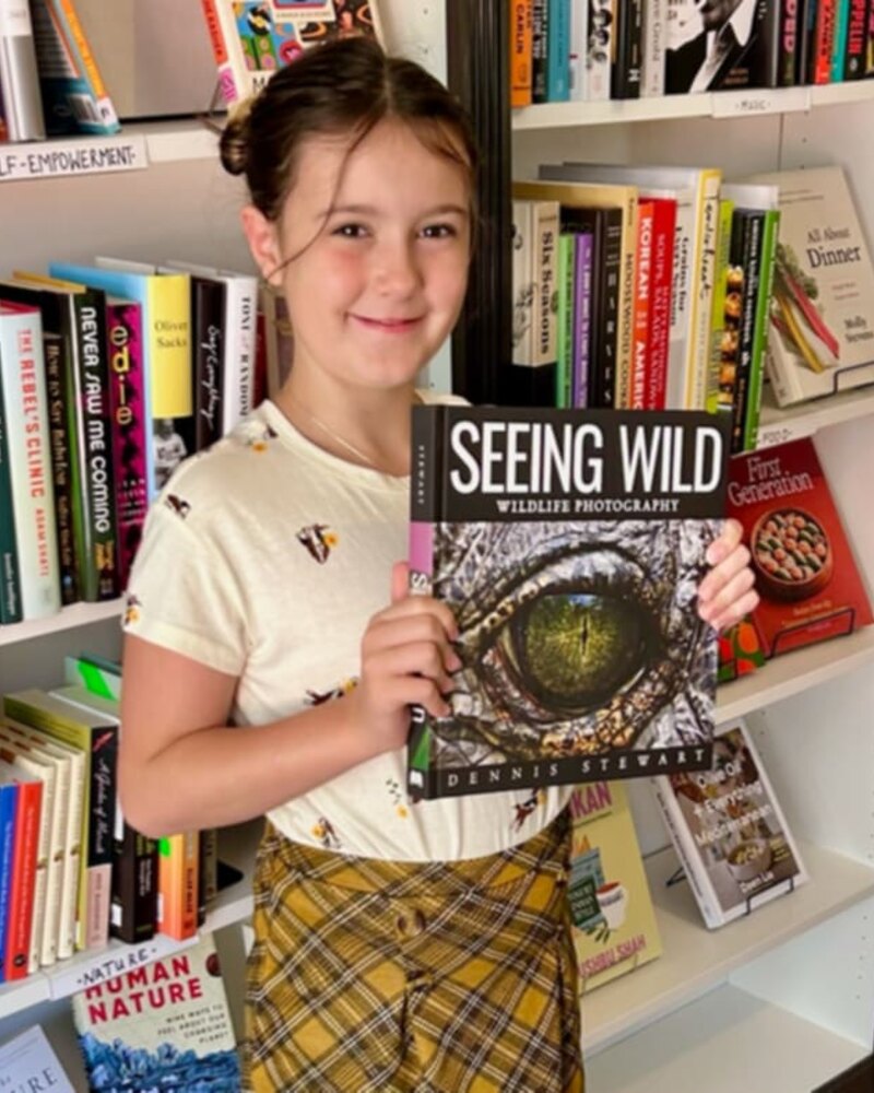 Young reader holding Seeing Wild among books